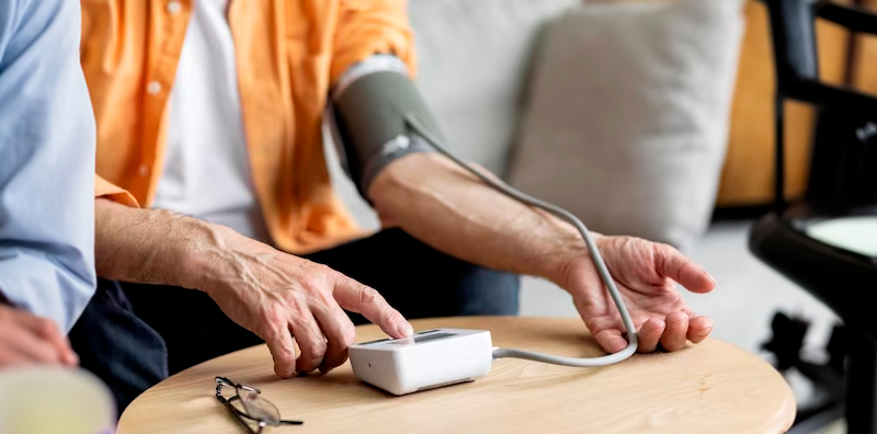 Un profesional de Seymad Care midiendo la tensión arterial de un cliente mayor como parte de nuestra asistencia en el hogar.