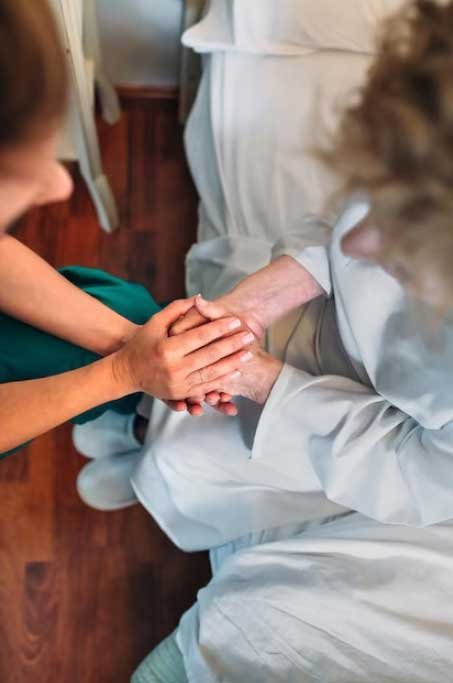 Cuidadora de SeymadCare dando la mano a una persona mayor en señal de acompañamiento hospitalario